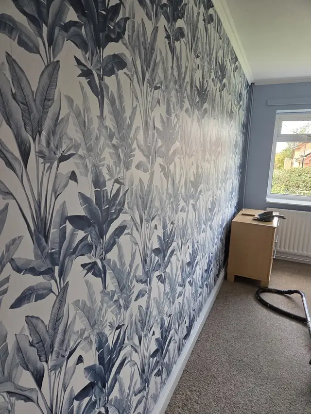 Blue botanical feature wallpaper hung along a living room wall