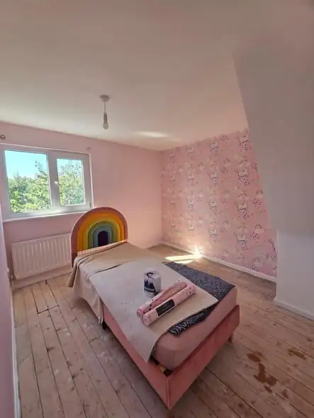 Pink child's bedroom with a rainbow unicorn wallpaper wall