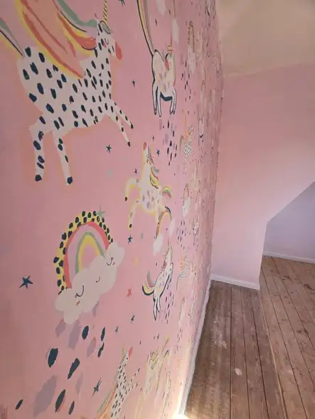 Close-up of a unicorn mural wallpaper on a pink feature wall